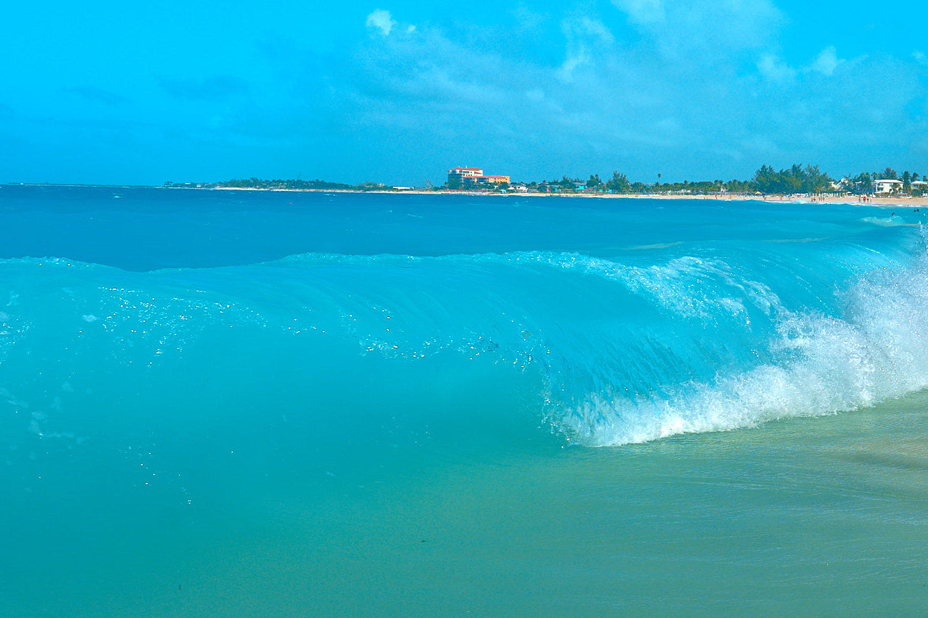 Turquoise ocean waves crashing onto a sandy beach with a clear blue sky.